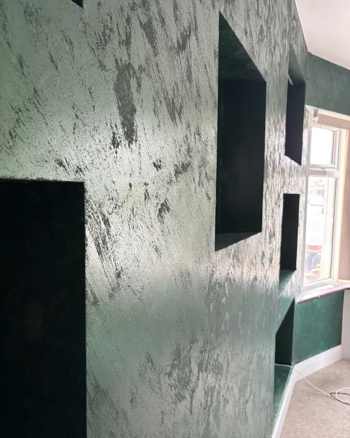 A deep green polished plaster feature wall with a mottled metallic sheen, square recesses cut into its face.