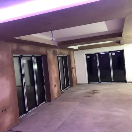 A wide plastered interior with bifold doors along one side and a dropped ceiling washing coloured cove light across fresh plaster.